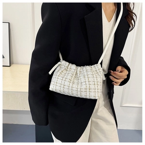 Nahaufnahme der eleganten Tweed-Tasche in Weiß und Gold mit weicher Textur und Lederriemen