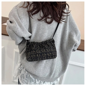 Detail der Tweed-Umhängetasche mit Goldgitter, getragen über einem grauen Pullover