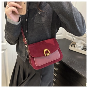 Macro view of burgundy suede flap bag featuring vintage gold horseshoe buckle and texture