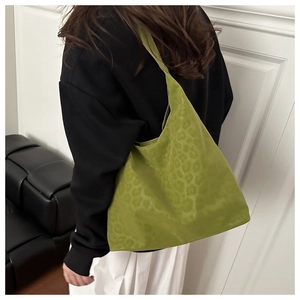 Detailed view of green leopard print tote bag on shoulder with leopard pattern texture