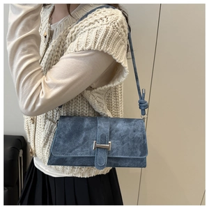 Close-up of navy blue suede baguette bag featuring silver buckle and knot strap detail
