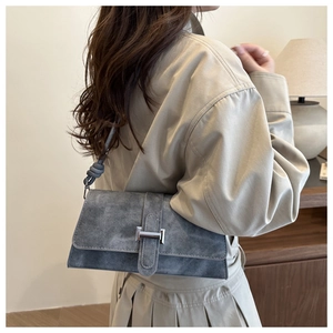 Detail of grey suede shoulder bag featuring silver buckle and knot strap design
