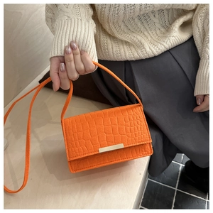 Détail du sac bandoulière orange vif à motif crocodile et boucle en métal doré