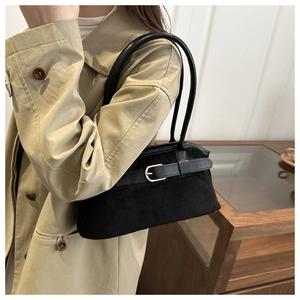 Détail d'un sac à bandoulière en daim avec boucle dorée sur un mannequin en trench