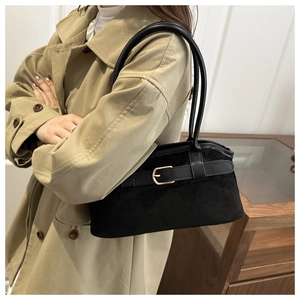 Detailed close-up of a black suede shoulder bag with elegant gold metal buckle hardware