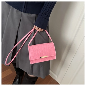 Détail du petit sac rose à motif pierre porté avec un pull bleu marine et une jupe grise