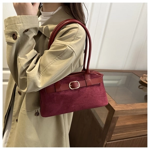 Detail of burgundy suede shoulder bag with gold buckle on trench coat model