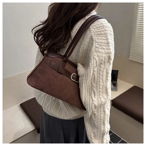 Détail du sac à bandoulière en daim marron foncé avec design trapèze vintage et boucle dorée