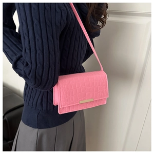Détail de la texture cuir de crocodile rose avec un élégant accent en métal doré