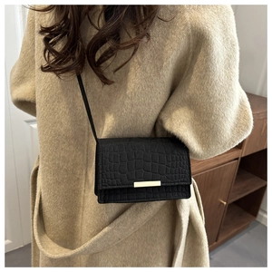 Détail du sac à bandoulière noir motif crocodile avec boucle en métal doré élégante