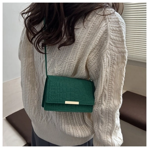 Détail du sac bandoulière vert en feutre avec texture crocodile et fermoir doré chic