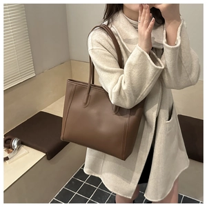 Detailed texture of a dark brown faux leather tote bag with sturdy shoulder straps