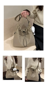 Detail view of khaki nylon tote bag with drawstring closure and plush cloud charm