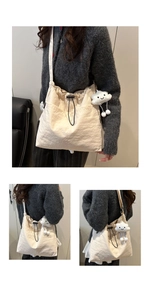 Detail of a large beige nylon tote bag with drawstring closure and cloud plush pendant
