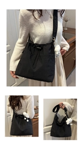 Detail of black nylon drawstring tote with a white cloud plush charm and adjustable strap
