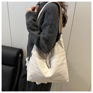 Detail view of large white nylon tote bag with drawstring pocket and smooth texture