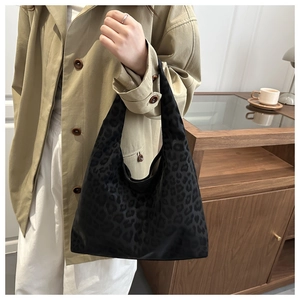 Detail of a dark leopard print tote bag worn on shoulder, showing high-quality fabric texture
