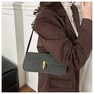 Detail of dark leopard print suede shoulder bag with gold metal buckle on a model