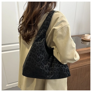 Detail of a black leopard print tote bag with soft velvet texture on a model's shoulder
