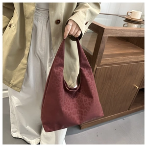 Detail of dark red leopard print tote bag with thick fabric texture and integrated handle