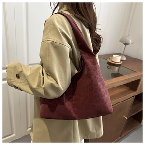 Detail of burgundy leopard pattern tote bag worn with a casual trench coat