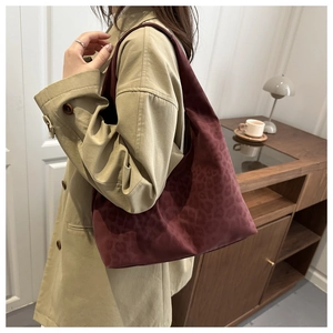 Detail view of burgundy tote bag featuring subtle leopard print and wide shoulder strap