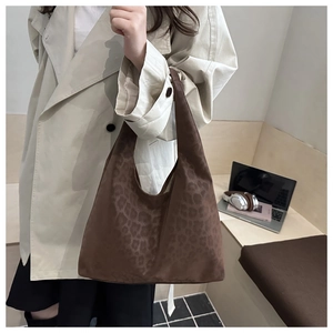 Detail of dark brown leopard print tote bag with soft suede texture on a model
