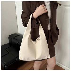 Close-up of cream white PU leather tote bag held by a model in a minimalist setting