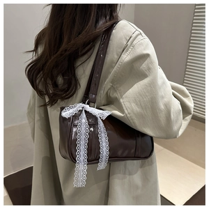 Brown vintage faux leather handbag with white lace bow detail shown on model's shoulder
