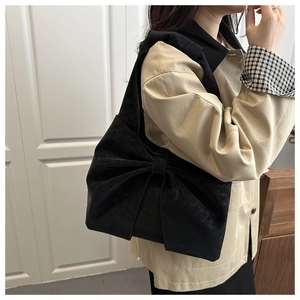 Detail view of stylish black denim shoulder bag with a large oversized decorative bow knot
