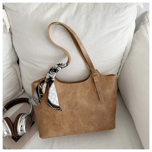 Detail of caramel faux leather tote bag with elegant polka dot scarf on strap