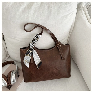Detailed macro view of the brown leather tote bag with elegant silk scarf decoration