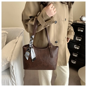Détail d'un sac cabas marron foncé avec foulard imprimé et trench-coat kaki élégant