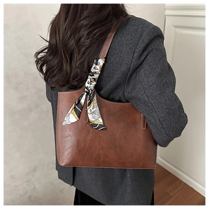 Vintage brown leather tote bag with decorative printed silk scarf on a shoulder strap