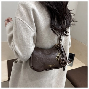 Detail of dark brown cracked leather shoulder bag with gold zipper and unique charms