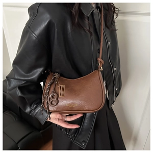 Détail du sac à bandoulière vintage marron en demi-lune avec logo et breloques dorées