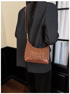 Fashionable leopard print crescent bag with adjustable shoulder strap and logo detail