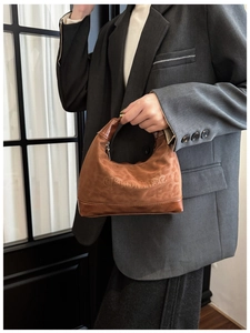Detail of brown vintage leather tote bag showing qaanse logo and textured finish