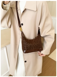 Close-up of leopard print shoulder bag with brown leather bottom and gold buckle
