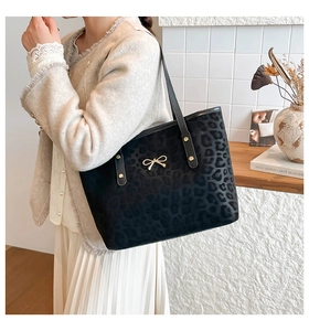 Close-up of leopard print suede tote bag featuring a decorative golden bow hardware detail