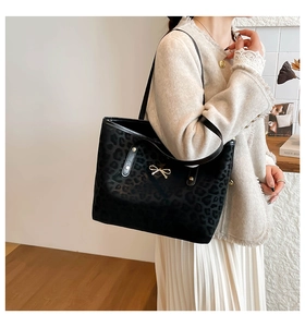 Close-up of leopard print tote bag featuring a gold bow detail and leather shoulder strap