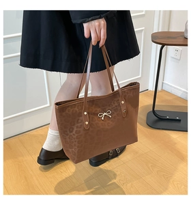 Close-up of leopard print tote bag featuring a decorative gold bow and textured finish