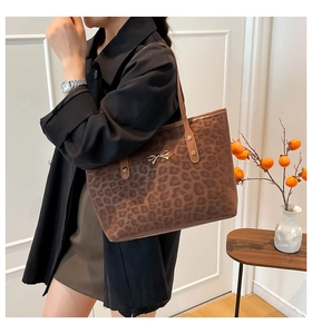 Brown leopard print tote bag with a golden bow detail shown on shoulder with long straps