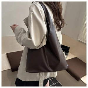 Vista laterale della grande borsa tote marrone minimalista in pelle PU opaca