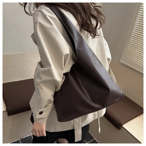 Dettaglio di una grande borsa tote marrone scuro in ecopelle con tracolla larga e stile minimal