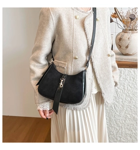 Detail of black saddle shoulder bag featuring suede patchwork and silver hardware