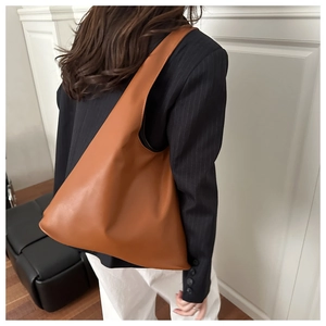 Dettaglio laterale di una borsa hobo minimalista in pelle marrone caramello con finitura opaca