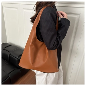 Detail view of large brown faux leather tote bag showing soft texture and wide strap