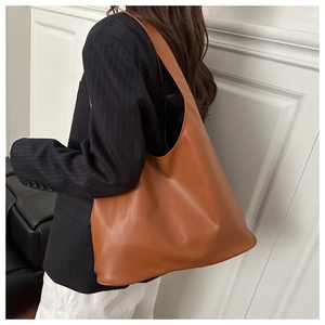 Dettaglio della grande borsa tote in ecopelle marrone con cuciture e tracolla larga morbida