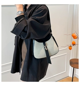 Close-up of crescent shoulder bag featuring grey suede, black leather trim and silver metal clasp